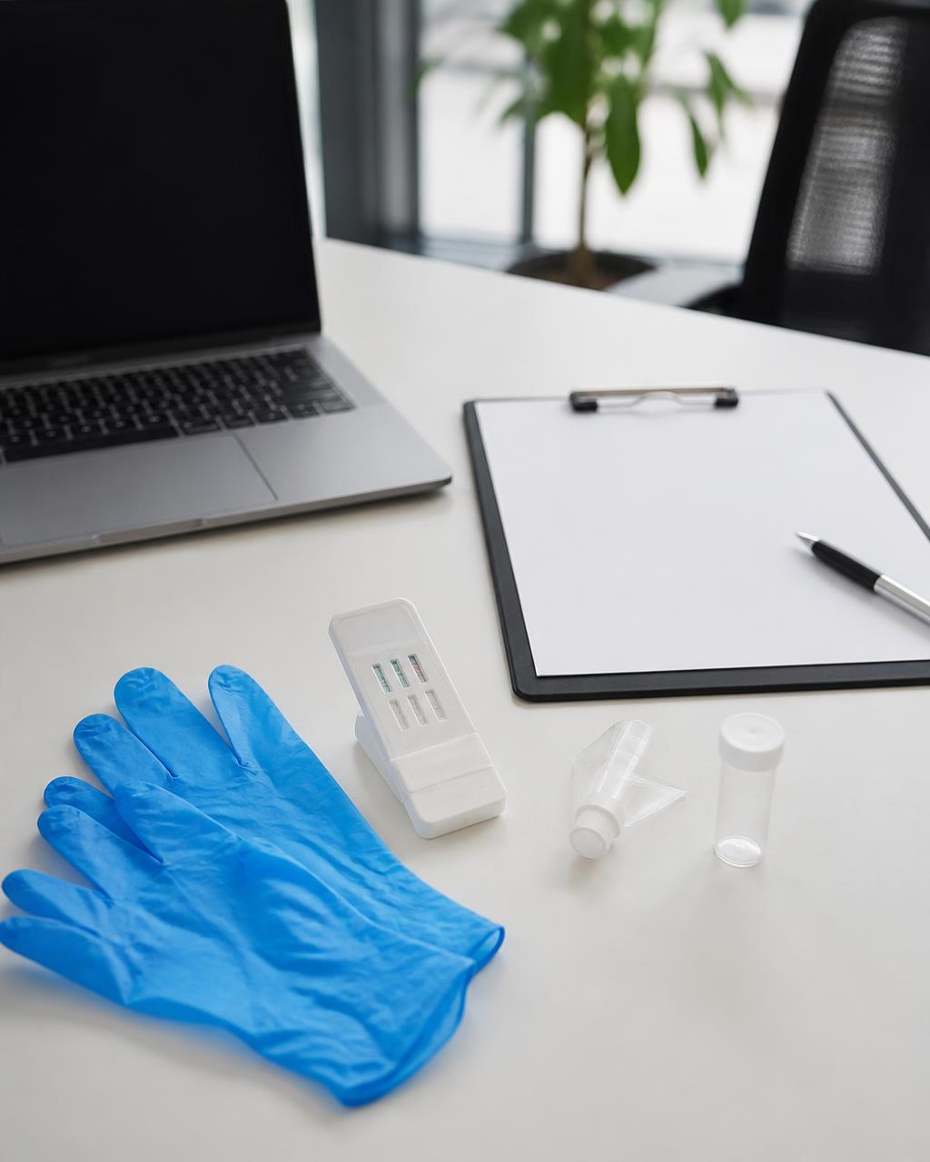 Rapid drug screen test kit, gloves, and employer paperwork on a clean office desk